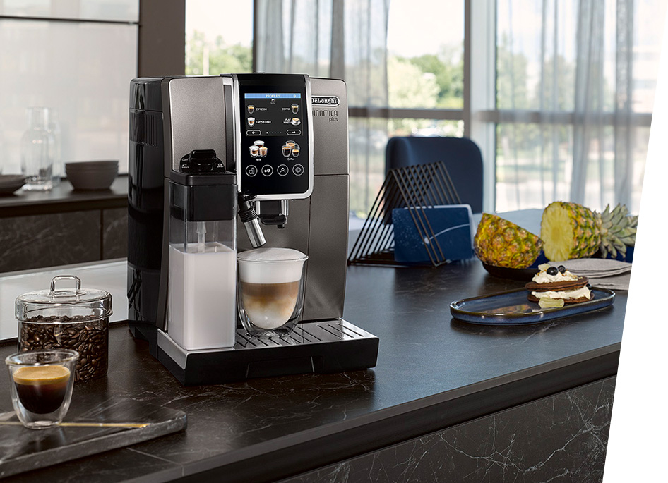 Ekspres do kawy z mlekiem, obok kawa, ananas i deser na blacie kuchennym.