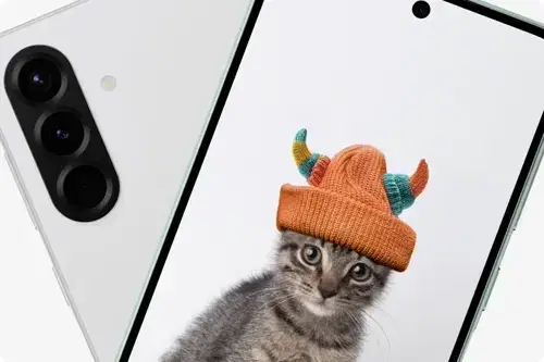 Dwa telefony. Biały telefon z trzema obiektywami aparatu. Ekran drugiego telefonu pokazuje kota w pomarańczowej czapce z rogami.
