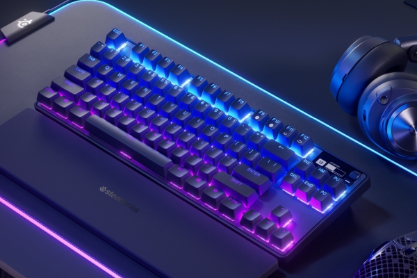 Klawiatura z podświetleniem RGB leży na podkładce obok słuchawek i myszki, całość w odcieniach fioletu i niebieskiego.