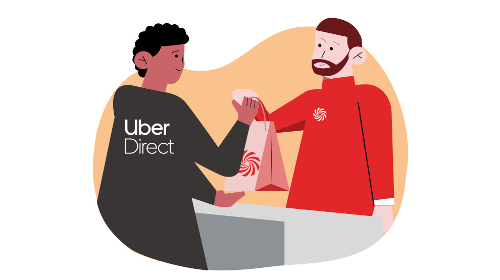 Mężczyzna w czarnej kurtce z napisem "Uber Direct" przekazuje torbę klientowi w czerwonej bluzce z logo na tle beżowego kształtu.