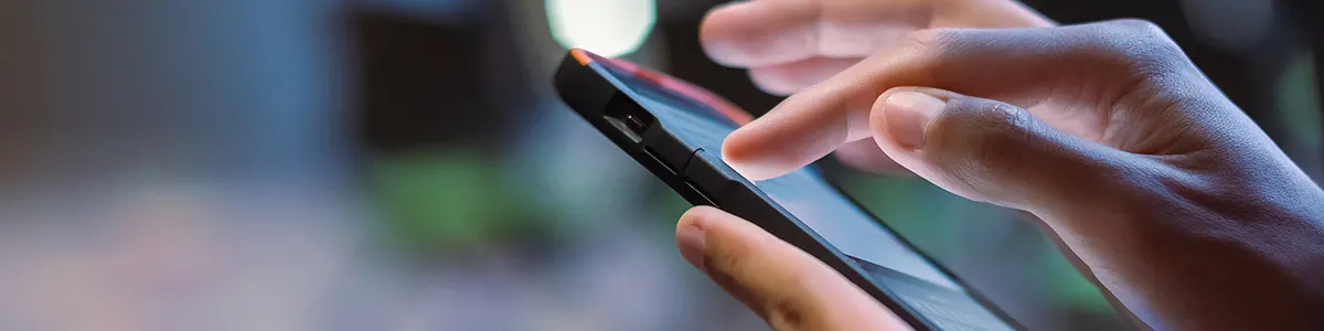 Kobieta dłonią dotyka ekranu smartfona i czyści telefon ze zbędnych plików.