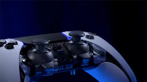 Zbliżenie kontrolera konsoli PlayStation 5, z czarnymi gałkami analogowymi i białymi elementami obudowy, na ciemnoniebieskim tle.