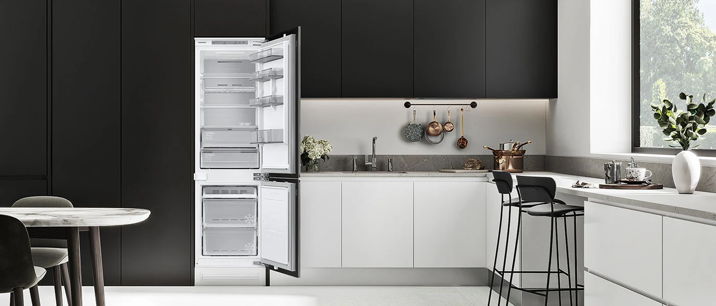 Nowoczesna kuchnia z czarnymi szafkami i białymi blatami. Otwarta biała lodówka, stół z krzesłami, okno. Naczynia wiszą na relingu.