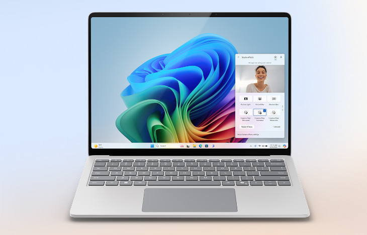 Laptop z klawiaturą i touchpadem na jasnym tle. Na ekranie kolorowa grafika i okno rozmowy wideo.