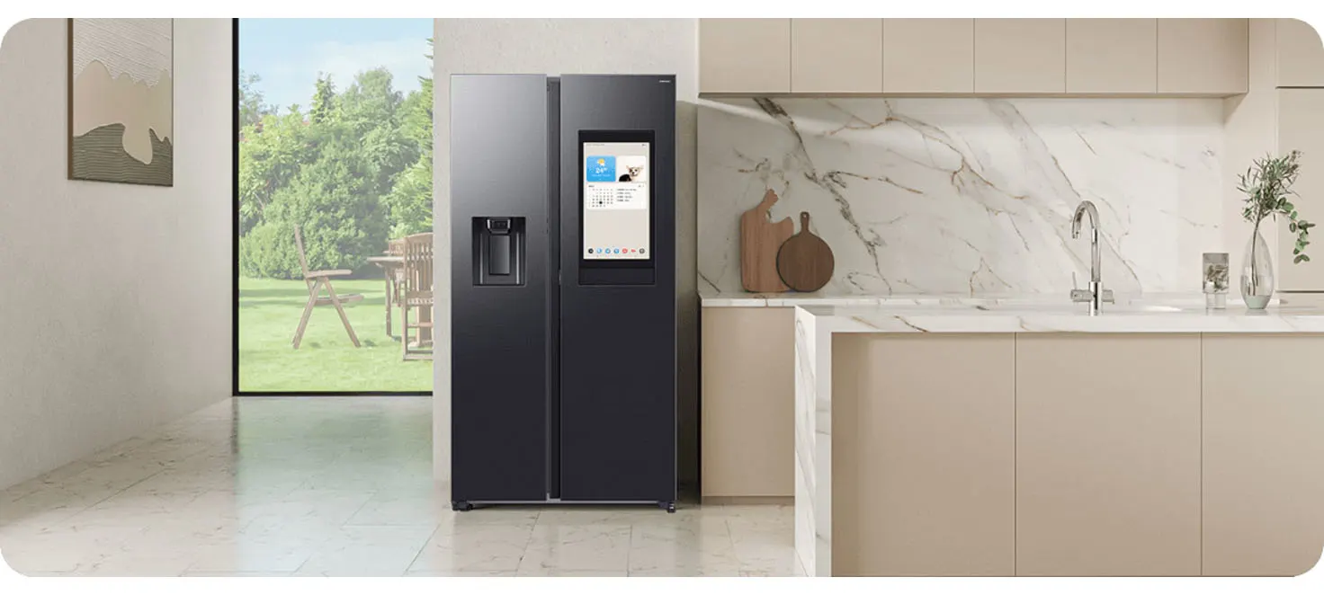 Wnętrze kuchni z czarną lodówką Samsung z ekranem, beżowe szafki, marmurowy blat i zlew. Za oknem ogród z krzesłami.