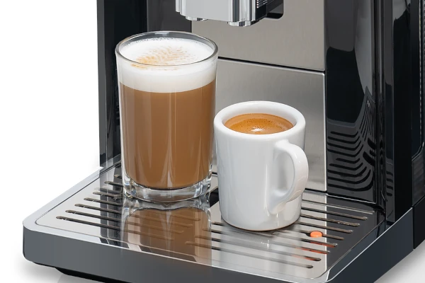 Automatyczny ekspres do kawy KOENIC Cremaro+ z wysoką kawą mleczną i filiżanką espresso na metalowym ociekaczu.