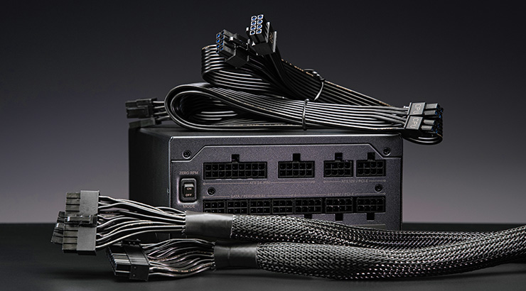 Czarny zasilacz komputerowy z licznymi czarnymi kablami i złączami na ciemnym tle.