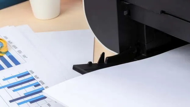 Drukarka dla studenta na biurku z wydrukami wykresów.