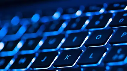 Czarno-niebieska klawiatura podświetlana od spodu. Widoczne litery J, K, L, O, P oraz cyfra 0 i znak zapytania.