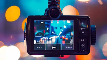 Czarna kamera samochodowa nagrywa obraz ulicy w nocy, w tle rozmazane światła.