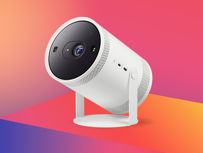 Biały, cylindryczny projektor Samsung The Freestyle na obrotowej podstawce, ustawiony pod kątem na kolorowym gradientowym tle; widoczna soczewka i perforowana obudowa.