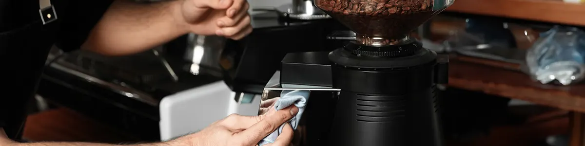 Mężczyzna czyści szmatką odkamieniony ekspres do kawy.