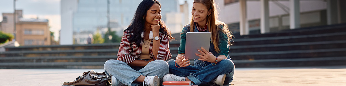 Uczniowie używają tabletów przed schodami. 