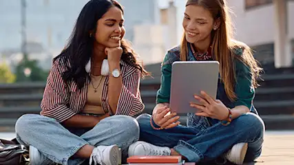 Uczniowie używają tabletów przed schodami.