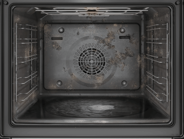 Wnętrze brudnego piekarnika z metalowymi półkami po bokach, z widocznymi zabrudzeniami na tylnej ściance i dnie.