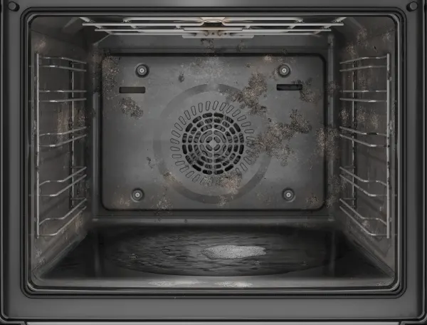 Wnętrze brudnego piekarnika z metalowymi półkami po bokach, z widocznymi zabrudzeniami na tylnej ściance i dnie.