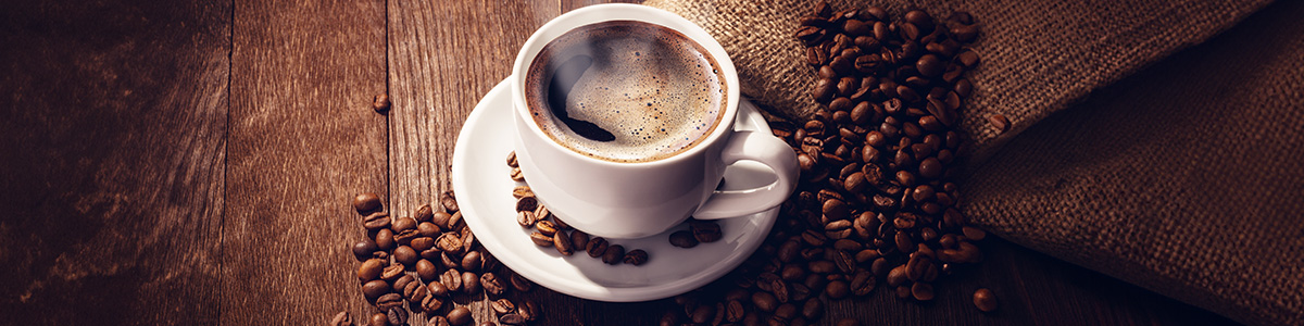 Filiżanka aromatycznego napoju stojąca na stole w otoczeniu ziaren kawy.