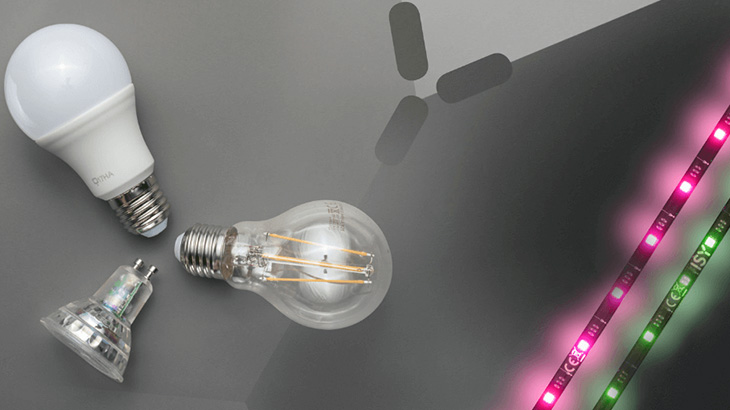 Na szarym tle leżą żarówki LED oraz taśmy LED w kolorach różowym i zielonym.