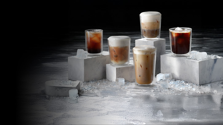 Na czarnym tle widać szklanki z napojami na białych blokach i kostkach lodu.