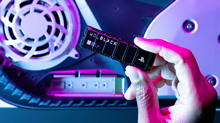 Dłoń trzyma czarny dysk WD Black SSD z logo PlayStation nad otwartym wnętrzem konsoli z białym wentylatorem.