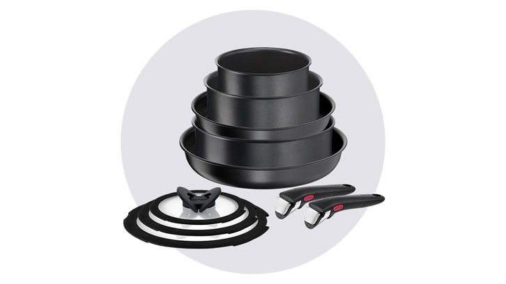 Na tle białego tła, na szarym okręgu, zestaw czarnych garnków ułożonych jeden na drugim, pokrywka i dwa odpinane uchwyty.
