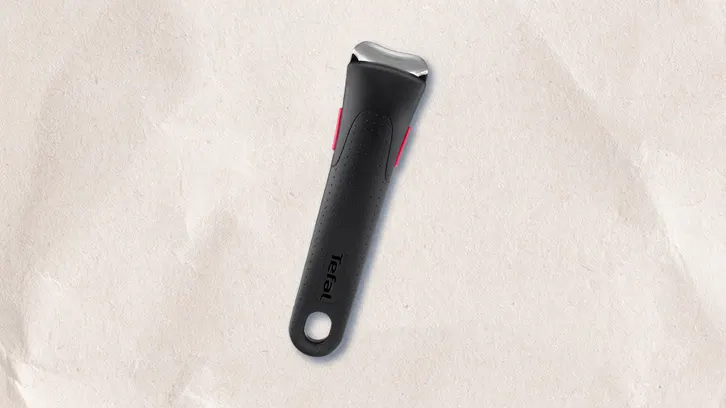 Czarny uchwyt Tefal z metalowym mocowaniem i czerwonymi akcentami na teksturowanym, kremowym tle.