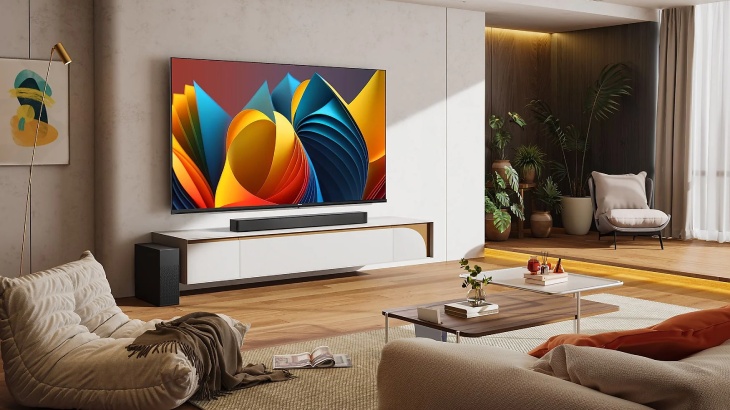 Salon z telewizorem, kanapą, stolikiem i roślinami. Na ścianie wisi abstrakcyjny obraz.