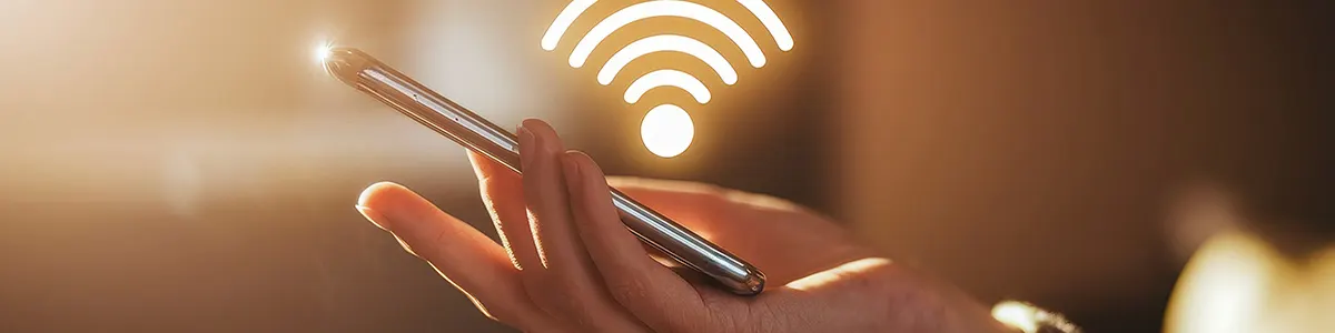 Mężczyzna trzymający smartfon i sprawdzający hasło do wifi na telefonie. W tle logo sieci bezprzewodowej.