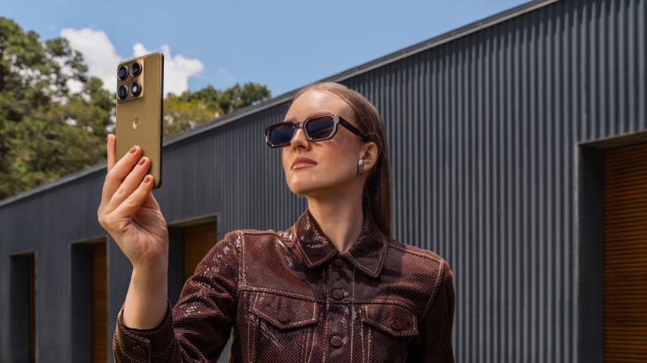 Osoba w okularach trzyma w rękach Motorolę Signature w wersji oliwkowej