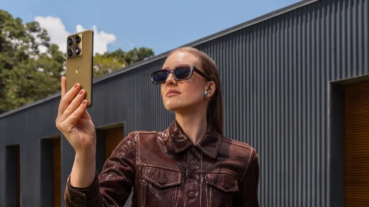 Osoba w okularach trzyma w rękach Motorolę Signature w wersji oliwkowej