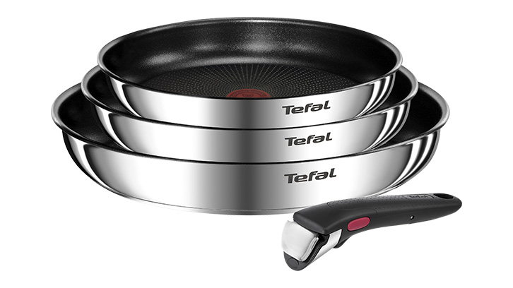 Na białym tle ułożone są trzy srebrne patelnie marki Tefal, jedna na drugiej, oraz czarny odpinany uchwyt.