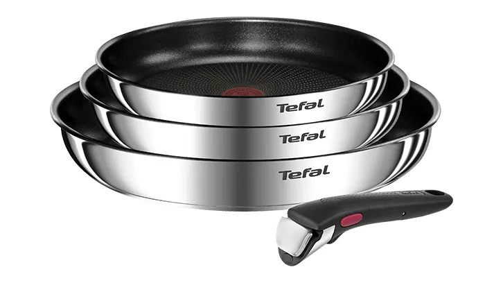 Na białym tle ułożone są trzy srebrne patelnie marki Tefal, jedna na drugiej, oraz czarny odpinany uchwyt.