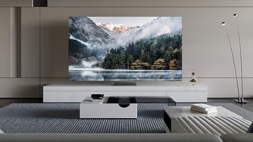 Salon z telewizorem wyświetlającym górski krajobraz, białe meble, szary dywan i lampę.