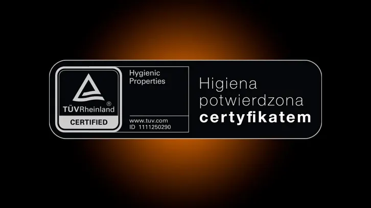 Grafika przedstawia czarny certyfikat z białym tekstem, potwierdzający higienę, z logo TÜV Rheinland na ciemnym tle.