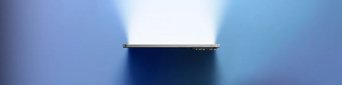 Telefon na niebieskim tle, oświetlony jasnym światłem. Widoczne obiektywy aparatu.