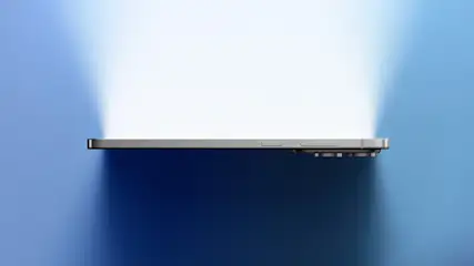 Telefon na niebieskim tle, oświetlony jasnym światłem. Widoczne obiektywy aparatu.