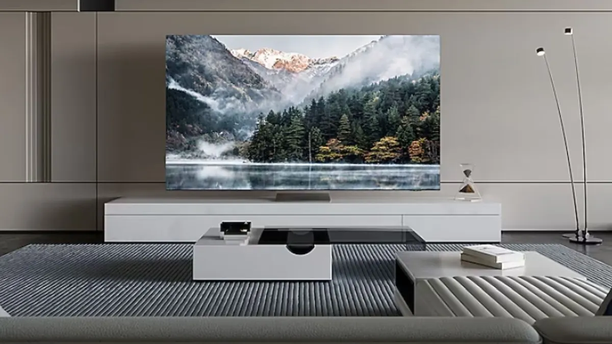 Salon z telewizorem pokazującym górski krajobraz, białe meble i szary dywan. Stojąca lampa z tyłu.