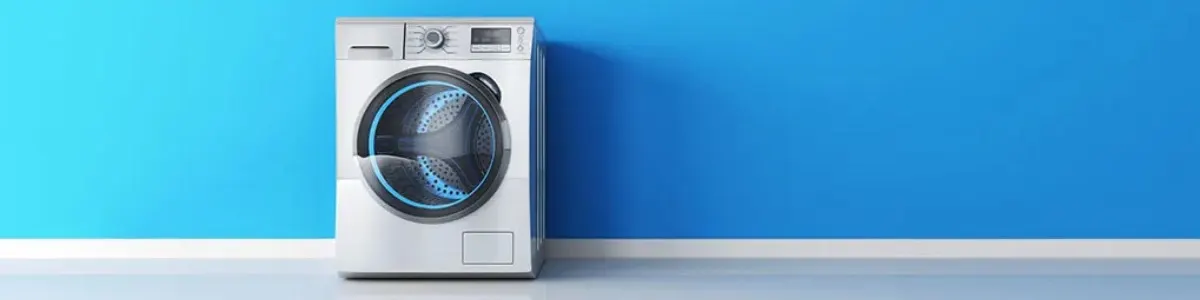 Biała pralka stoi na białej listwie przypodłogowej na tle niebieskiej ściany.