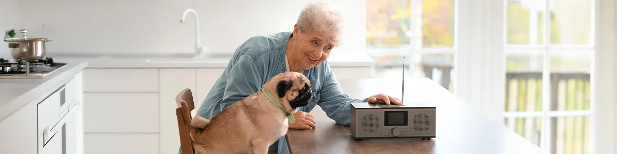 Staruszka razem z pieskiem słuchają radia w kuchni