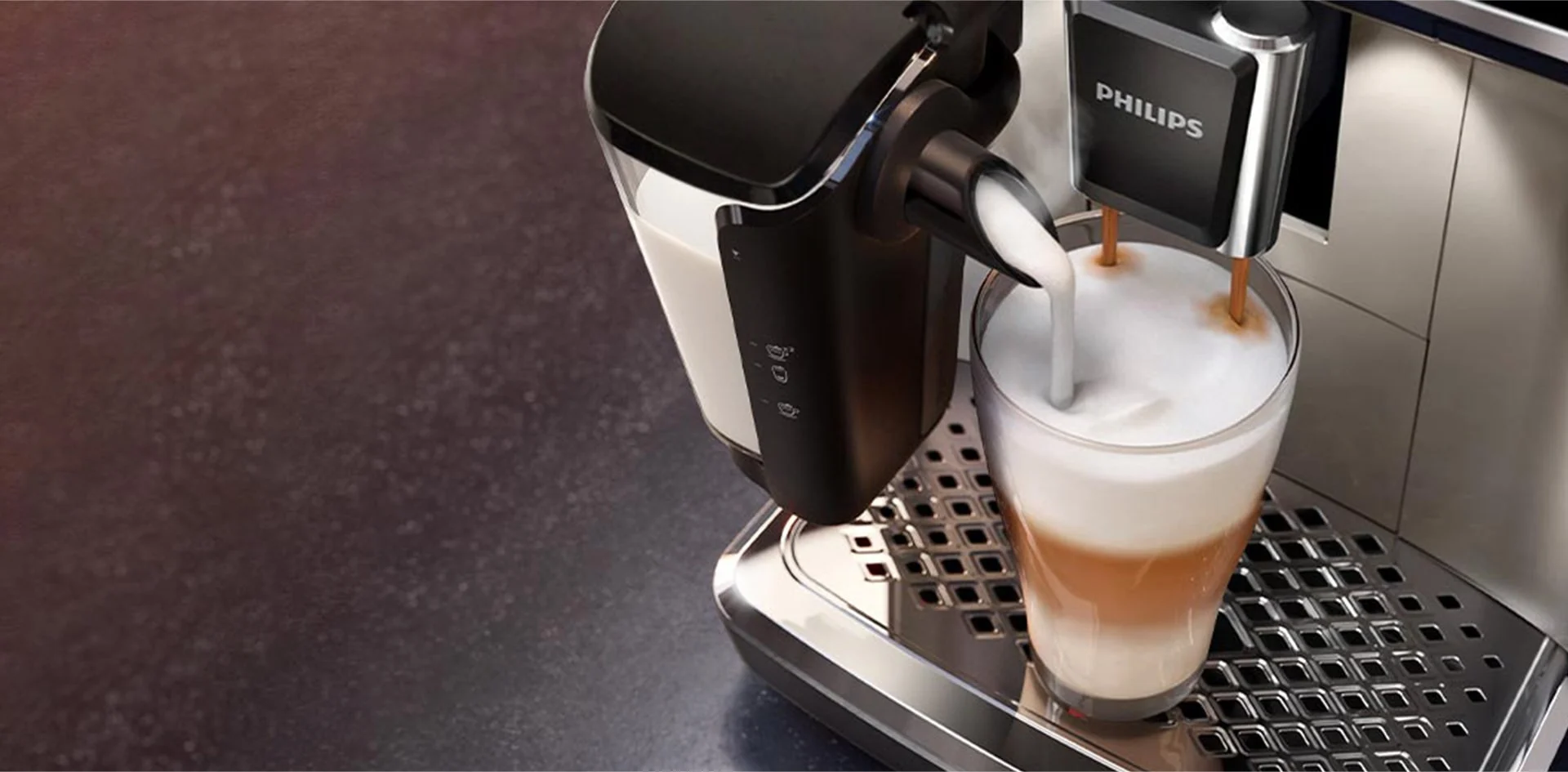 Kawa z mlekiem wlewana do szklanki na srebrnej tacce ekspresu Philips. Pojemnik na mleko po lewej stronie.