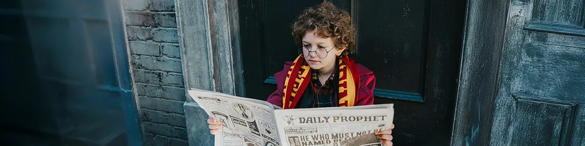 Młody fan Harry'ego Pottera przebrany w gadżety z ulubionego filmu