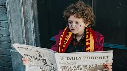 Młody fan Harry'ego Pottera przebrany w gadżety z ulubionego filmu