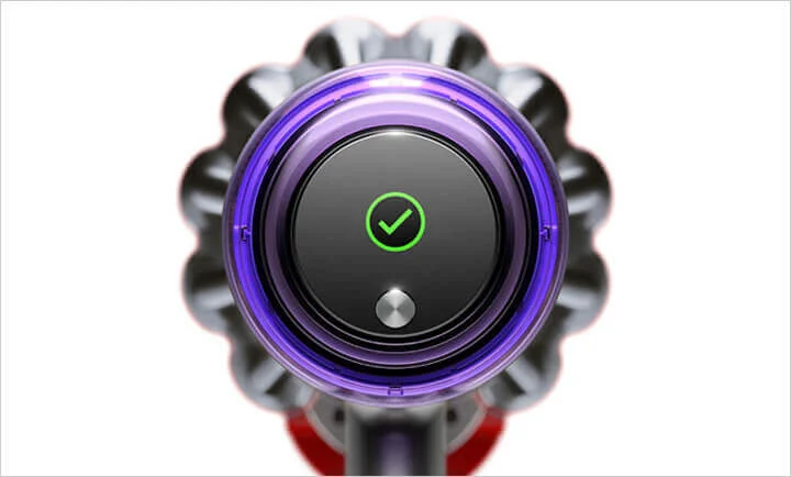 Zbliżenie na głowicę odkurzacza z fioletowym pierścieniem, czarnym panelem z zielonym symbolem zaznaczenia i srebrnym przyciskiem.