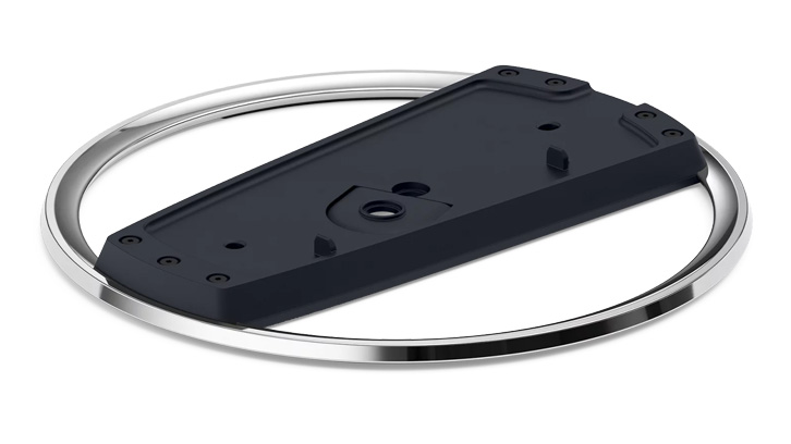 Czarny element z otworami na śruby leży na srebrnym, okrągłym elemencie na białym tle.