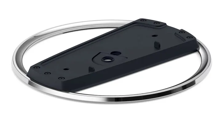 Czarny element z otworami na śruby leży na srebrnym, okrągłym elemencie na białym tle.