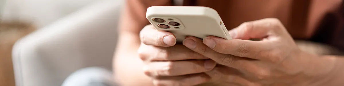 Mężczyzna ze smartfonem w rękach sprawdza, jaki ma model telefonu.