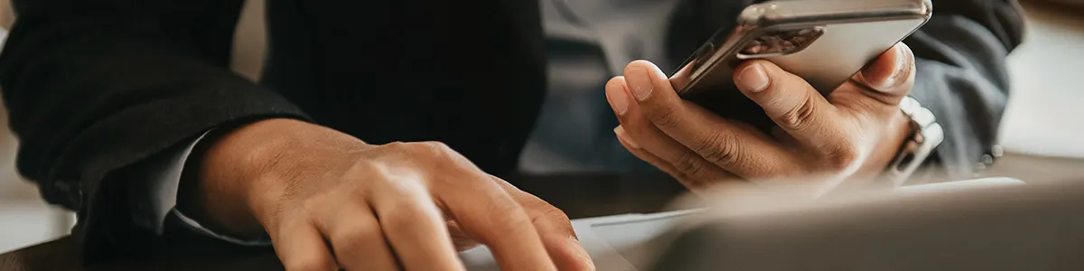 Mężczyzna w garniturze siedzi przy stole i bezprzewodowo zgrywa zdjęcia z telefonu na laptopa.