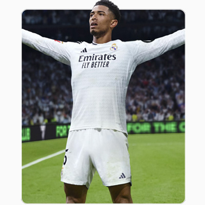 Na pierwszym planie piłkarz w białym stroju z rozłożonymi ramionami, na zielonym boisku, z widownią w tle.