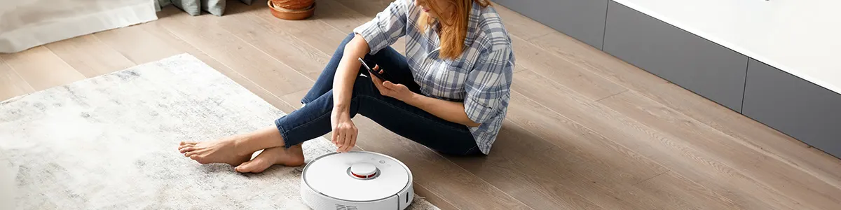 Kobieta programująca odkurzacz automatyczny z rankingu robotów sprzątających.