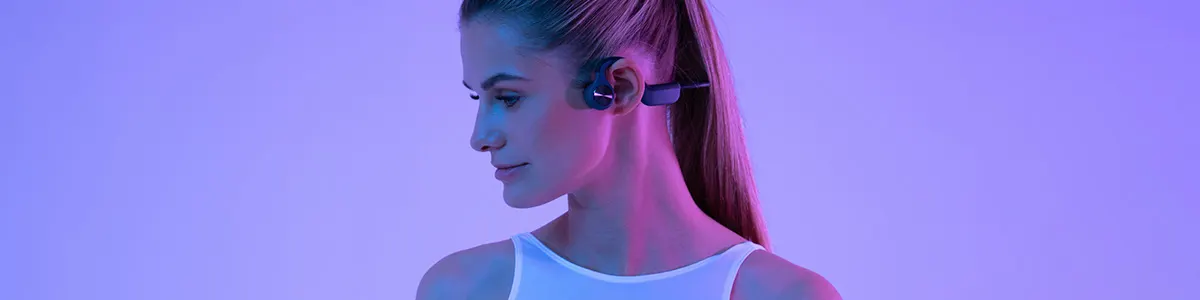 Kobieta ze słuchawkami kostnymi z rankingu na kolorowym tle.